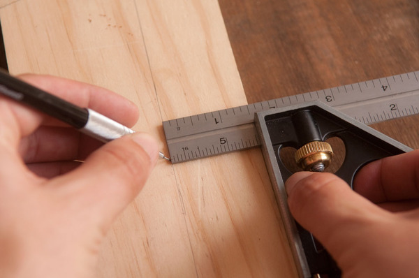 Marking a line on a wood board with a combination square