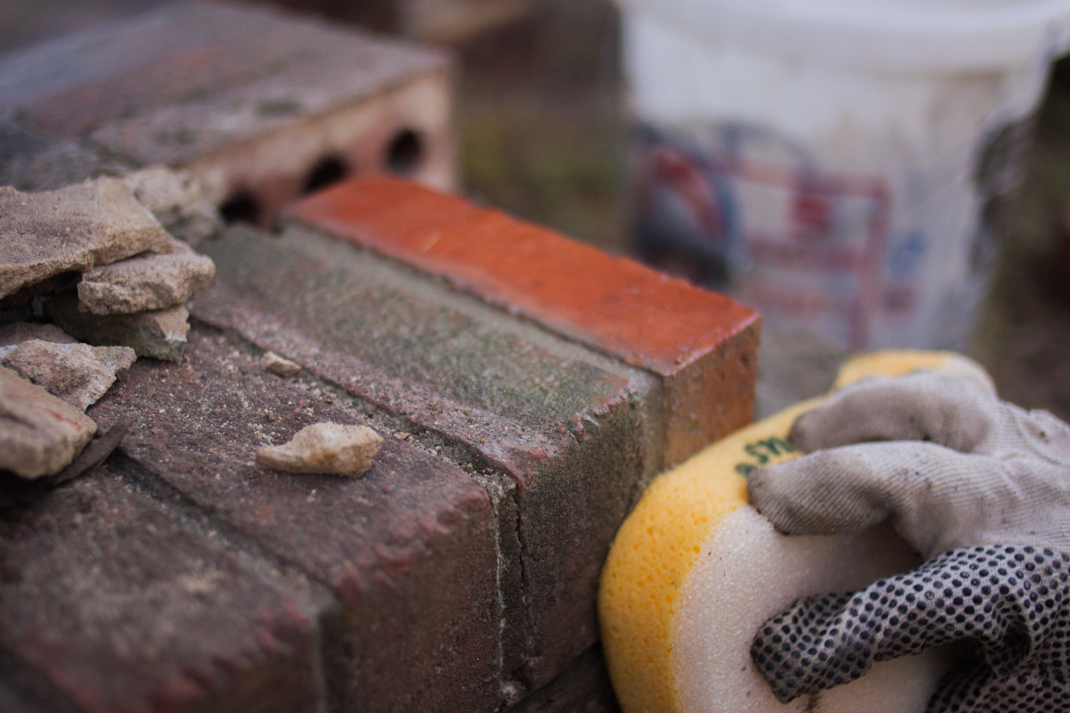 wiping excess mortar away from brick face with a grout sponge