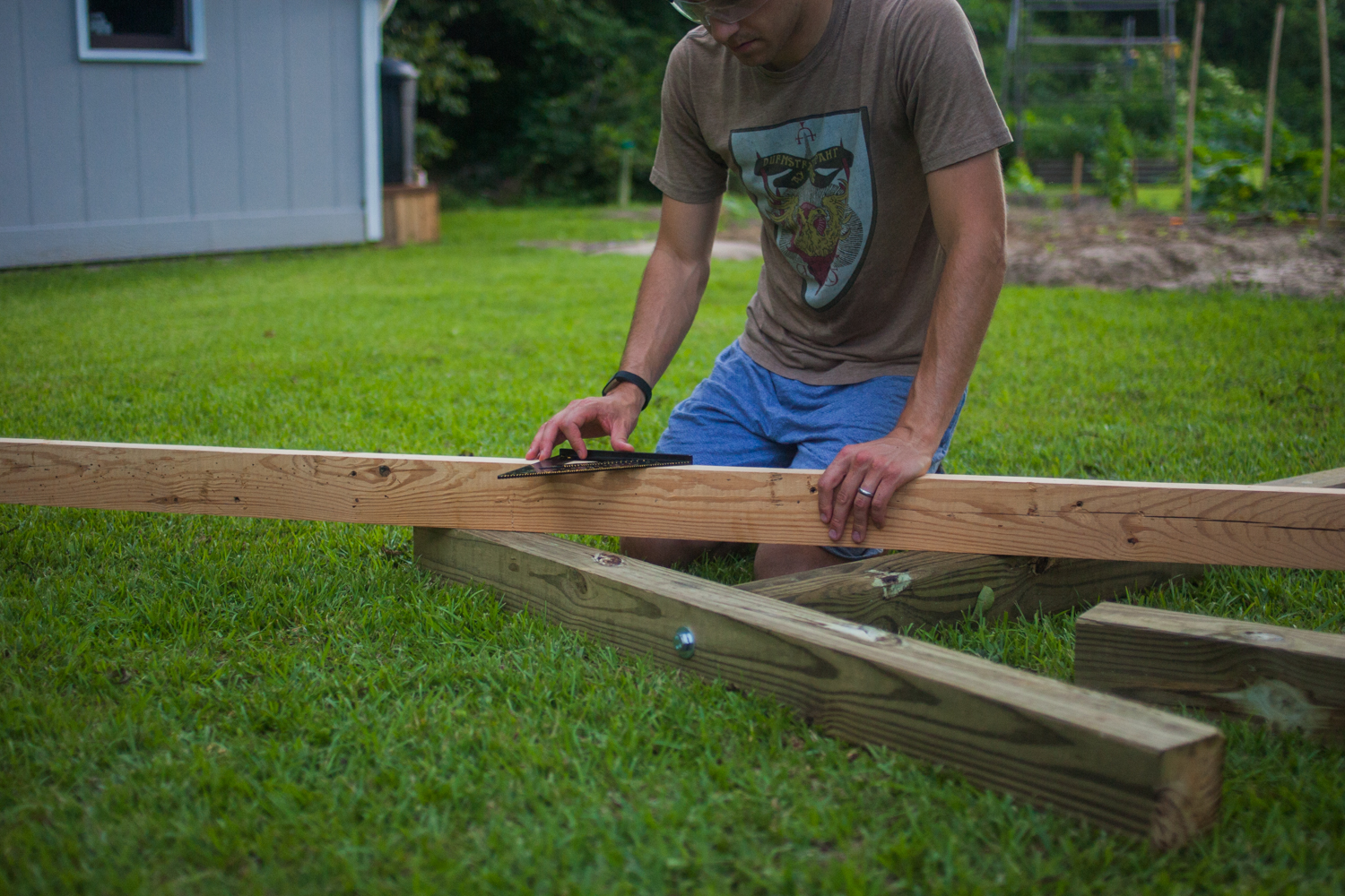 man using speed square on wooden post